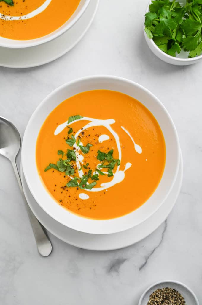 Overhead image of sweet potato soup in a white bowl, with a spoon on the left side.
